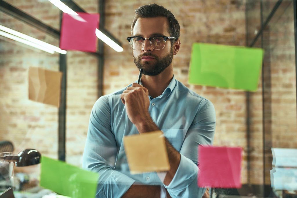 Startup. Young and handsome businessman in eyeglasses planning working process and using colorful